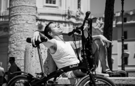 Street photography in Rome – cyclist resting in the city Man resting beside a folding bicycle in central Rome